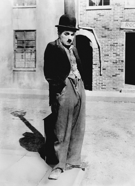 A dog 's life by and with Charlie Chaplin , standing in a street, hands in pockets. Los Angeles from English Photographer, (20th century)