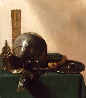 A still life of an overturned jug, a glass of wine, a bone on a plate, all on a green tablecloth