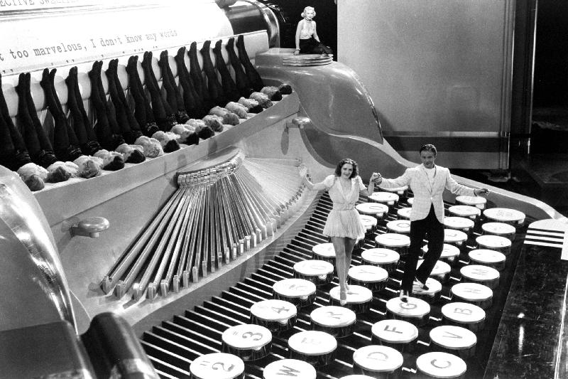 Couple dancing on the key of a giant typewriter, keys are leg of dancers, musical from 